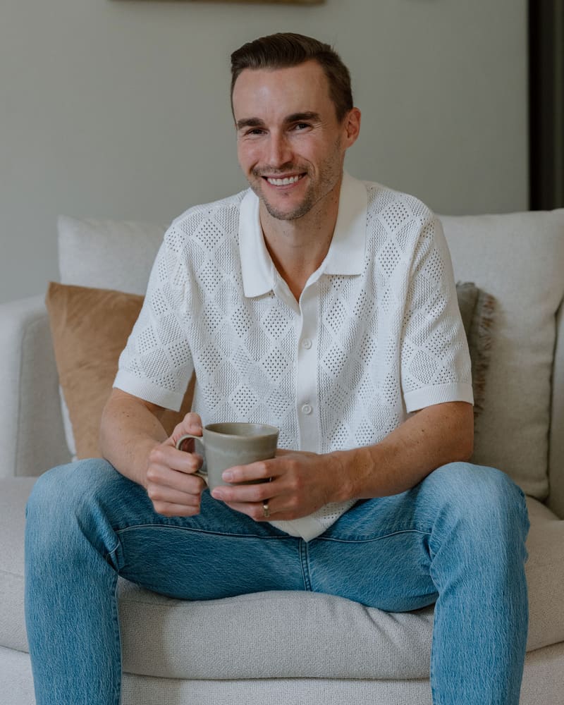 Garrett Larsen seated with a cup of coffee, smiling at the camera.